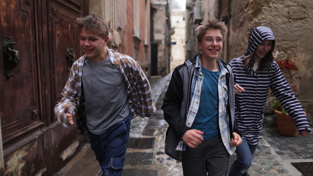 Three happy teenagers running in the rain