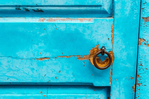 A weathered turquoise door with metal lock.