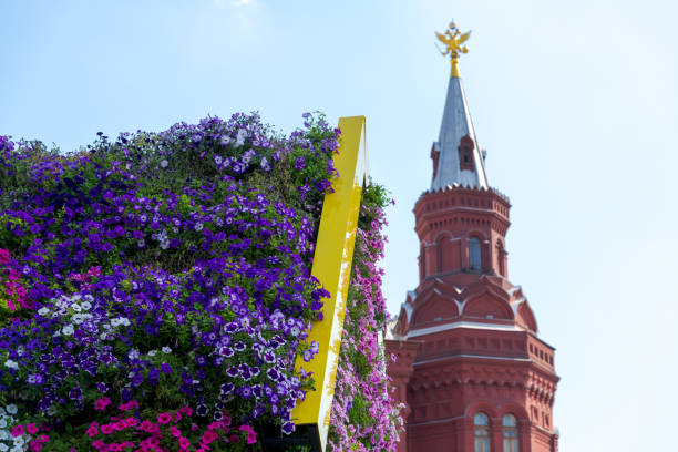Colourful building decorations with various petunia flowers on walls in a sunny summer day. Moscow Kremlin tower in the background. Soft focus. Summer flower festival theme.