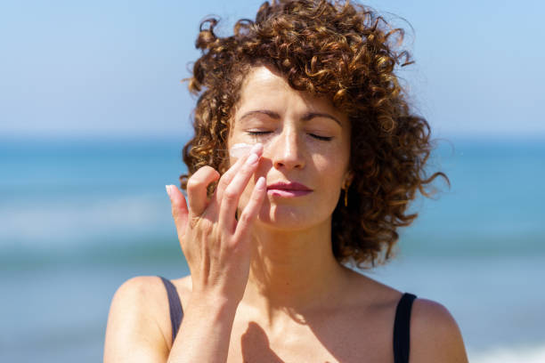 Sensual woman applying sunscreen on face stock photo