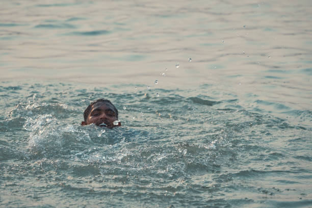 Babughat, Kolkata, 06/11/2023: a young guy cooling off the heat in a hot summer day, by taking bath in Ganges river.