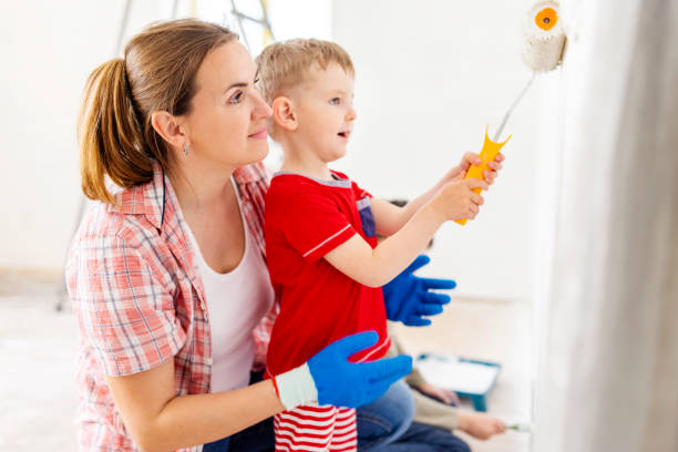 istock Mother and child son paint the wall with paint using roller and brush 1497951632