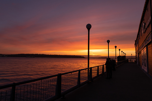 Seattle, USA - Feb 12th, 2023: A vivid sunset over Elliott Bay from the Seattle Aquarium on the waterfront.