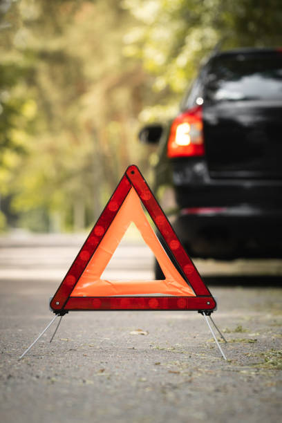 istock Red triangle, red emergency stop sign and black car with technical problems in the blurred background. Emergency stop of the car on the road. Safety procedure while having a vehicle broken down 1497955725