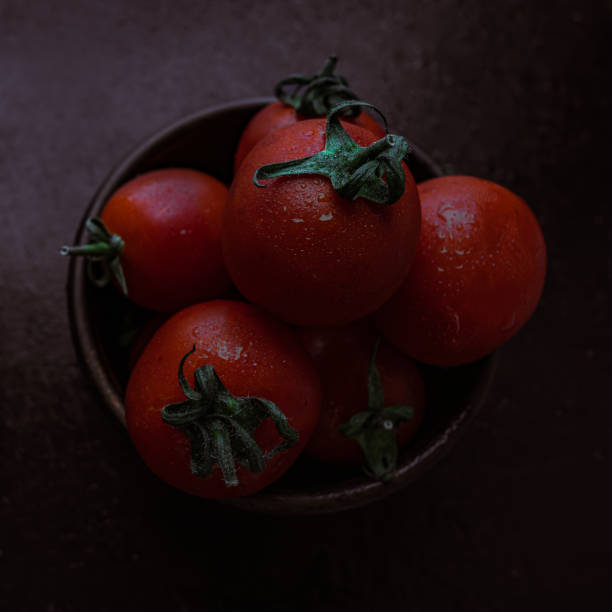 tomates de coquetel vermelhos maduros em uma tigela em uma mesa preta - healthy eating food and drink soup ripe - fotografias e filmes do acervo