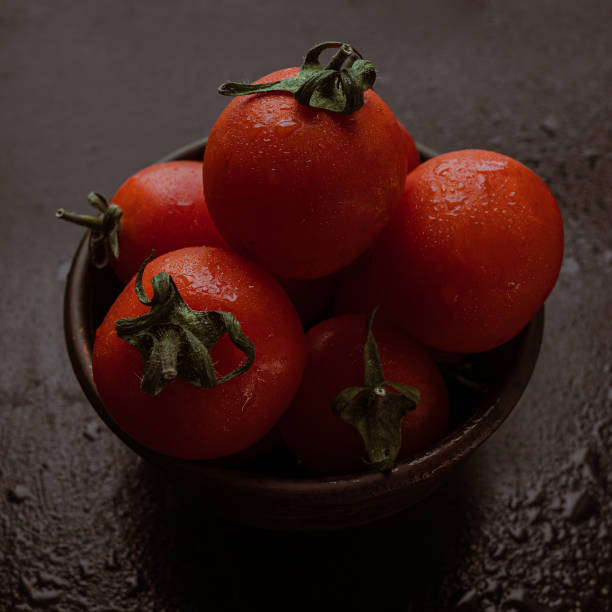 tomates de coquetel vermelhos maduros em uma tigela em uma mesa preta - healthy eating food and drink soup ripe - fotografias e filmes do acervo