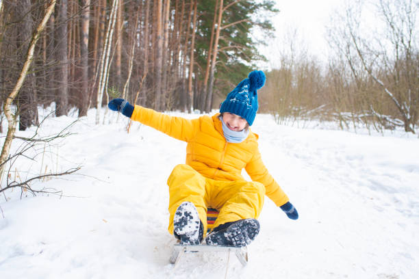 istock happy emotional smiling boy sledding in winter snowy forest 1497965835