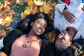 Two female friends lying down in autumn leaves and talking in secrets