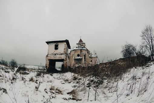 Ruins of an abandoned old church in the melancholic cold field.