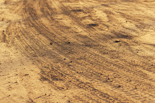 Tyre tracks on sand in orange tone. Abstract background and pattern.