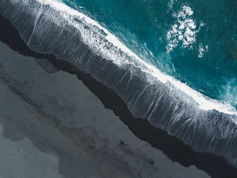 View on black sand and turquoise ocean from above