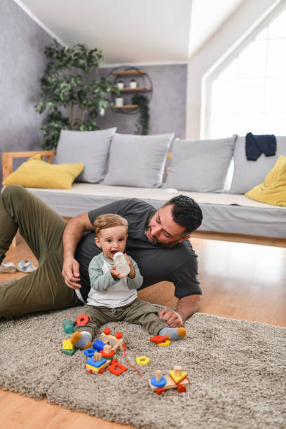 istock Cute Smiling Baby Boy Drinking Water While Being Looked After By Father 1497971719