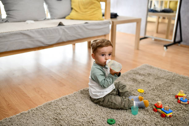 istock Small Baby Getting Thirsty After Playing On Floor And Drinking Water From Bottle 1497972566