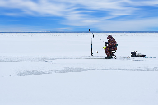 Ice fishing. lonely man fishing for perch. Winter fishing as hobby, Winter activity in Scandinavia. Hobby, winter free time concept