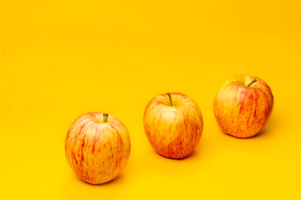istock Three red apple fruits on yellow background 1497981301