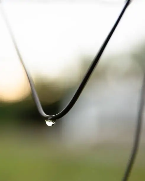 Photo of Shot of a metal wire, with water droplets suspended from its surface