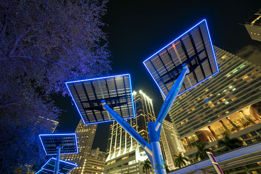 Blue solar photovoltaic panels mounted in modern city on street poles for electricity supply of streetlights and surveillance cameras. Futuristic energy source in downtown Miami, Florida.