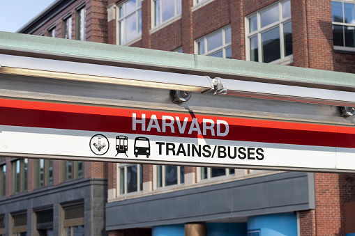 Cambridge, MA, USA - June 29, 2022: Harvard sign is seen at one of the entrances to the Harvard MBTA Station, a rapid transit and bus transfer station at Harvard Square in Cambridge, Massachusetts.