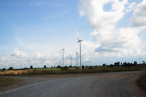 The road through the green field with wind turbine and blue sky, Wind farms, wind turbines, renewable energy from the wind.