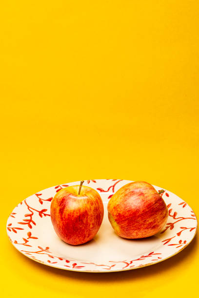 istock Two red apple fruits on yellow background 1497996389