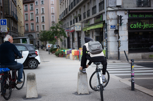 Grenoble, France: Two cyclists—a senior and a young man—wait to cross the street in downtown Grenoble.