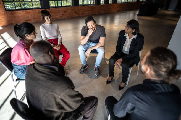istock Mid adult man talking during a therapy group 1497999953