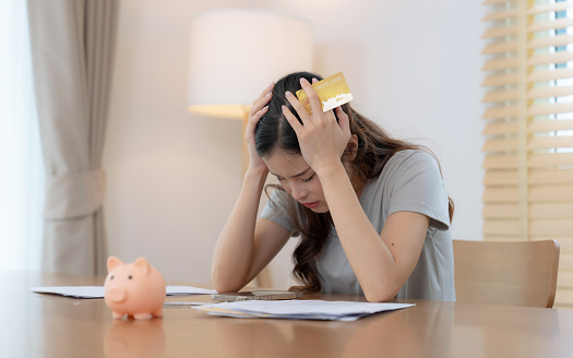 Stressed Asian woman seeing too high monthly expenses.