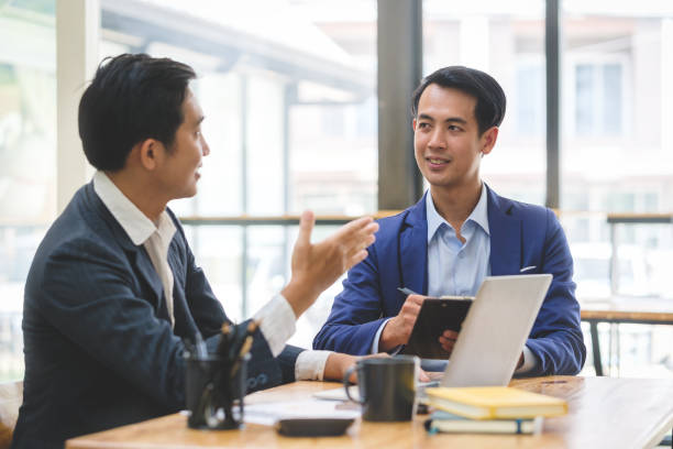 istock Two young business people sitting in modern office and discussing project strategy together. 1498006497