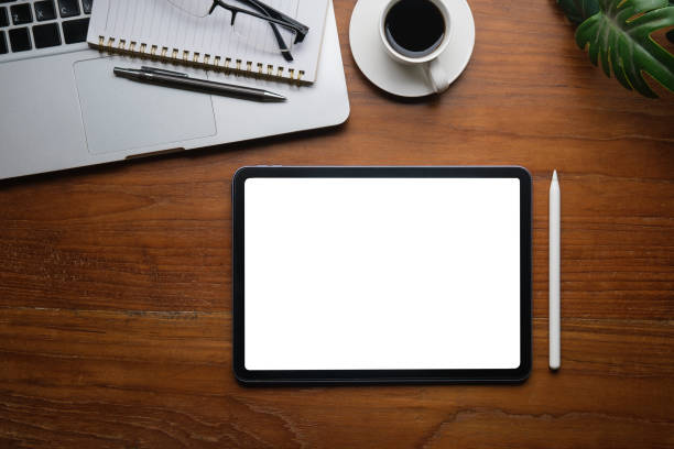 istock Flat lay, top view of digital tablet with blank display, laptop, notebook and coffee cup on wooden table. 1498006794