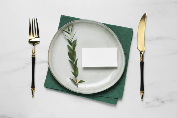 istock Stylish setting with cutlery, eucalyptus leaves and blank card on white marble table, flat lay. Space for text 1498009446