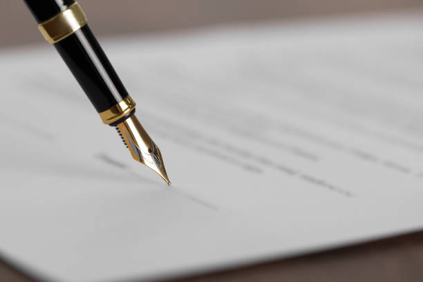 istock Writing on document with fountain pen at wooden table, closeup and space for text. Notary contract 1498009609