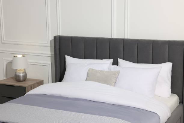 istock Comfortable bed near lamp on bedside table in stylish bedroom 1498009696