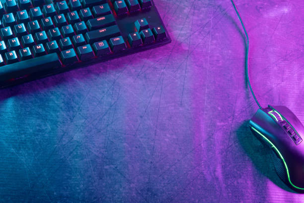 Top view with ample copy space of a gaming-themed desktop adorned with professional gaming accessories, illuminated by vibrant cyberpunk neon lights.