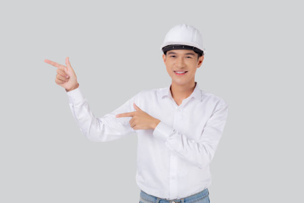 istock Portrait young asian man is engineer wearing helmet standing and smiling with confident isolated white background, male is architect or contractor presenting or showing something, industrial concept. 1498023483