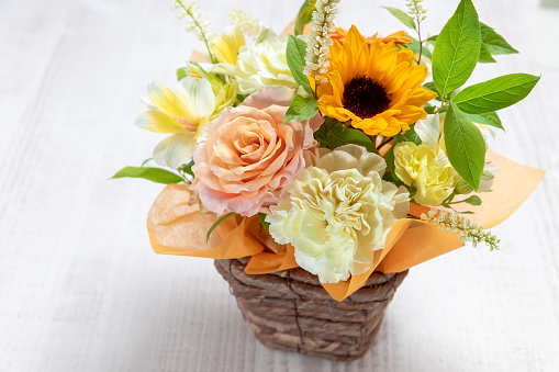 A large bouquet of multicolored flowers of different flowers isolated on a white wooden table.