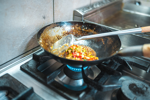 Close up shot of asian ingredients being cooked in a wok. Chef preparing a delicious dish while cooking on high fire.