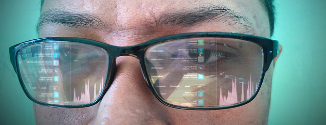 the reflection of the computer screen in the glasses, the programmer is seen working, he is wearing glasses, the reflection of the laptop screen is seen in the glasses
