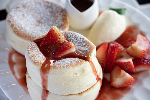 A plate of strawberry souffle pancake served with strawberry sauce and ice cream