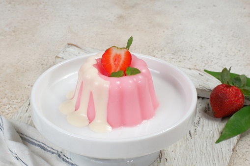 creamy strawberry pudding with sauce on a plate on a light background