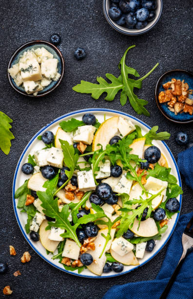 istock Gourmet salad with sweet pears, blueberries, blue cheese, arugula and walnuts. Black table background, top view 1498033972