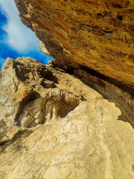 istock Winding mountain trail with large rock formations and a small cave entrance at the bottom 1498041515