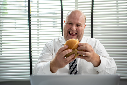 Fat man enjoy eating hamburgers for lunch.