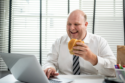 Fat man enjoy eating hamburgers for lunch.