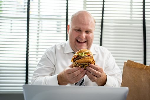 Fat man enjoy eating hamburgers for lunch.