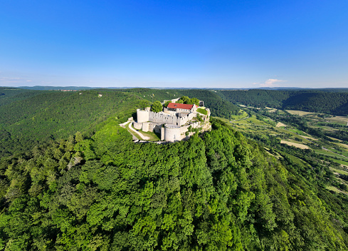 Neuffen, Germany - June 11, 2023: Swabian Alb in Summer. Drone view over the green summer swabian alb hills. Burg Hohenneuffen - Hohenneuffen Castle on top of green hill under blue summer sky. Neuffen, Hohenneuffen Castle, Esslingen, Swabian Alb, Baden Württemberg, Southern Germany, Germany, Europe.