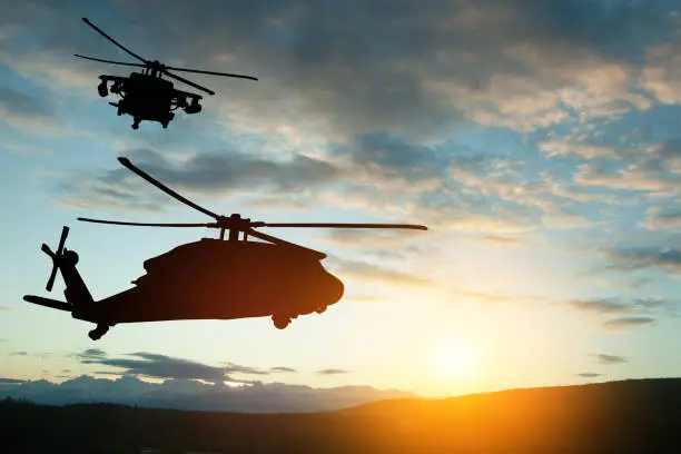 Photo of Silhouettes of helicopters on background of sunset.