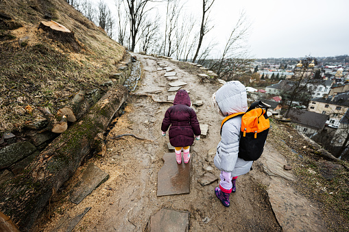 Two girls sisters walk up the wet path to an ancient fortress in rain.