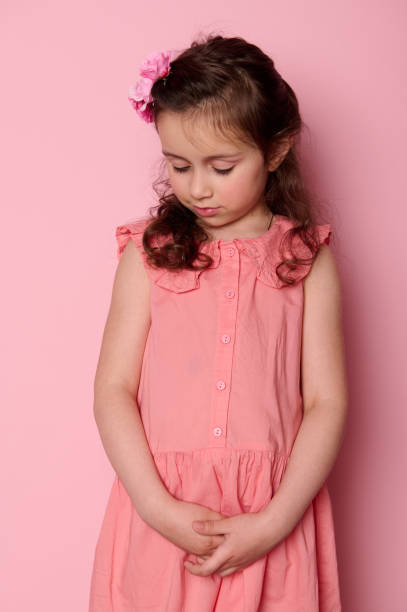 ピンクの背景に美しいコケット、5〜6歳の恥ずかしがり屋の少女�。キッズファッションと美容 - child little girls shy standing ストックフォトと画像