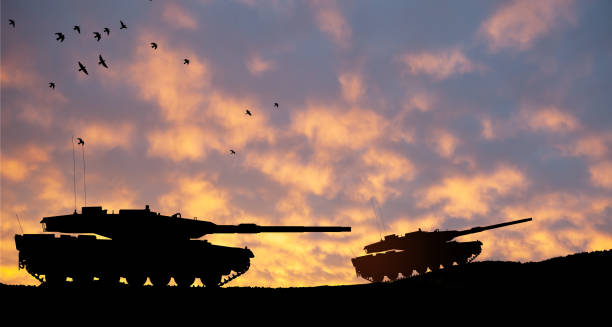 istock Silhouettes of army tanks at sunset sky background. 1498054190