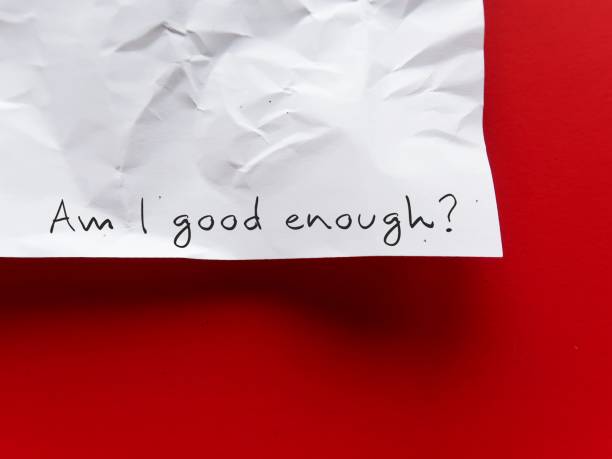 istock On copy space red background, crumpled paper with handwritten AM I GOOD ENOUGH? - negative self talk showing self doubt, inner voice with critical judgement - feeling not good enough 1498060066
